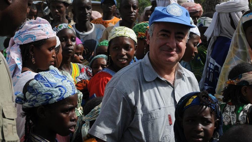 SRSG wearing a UN blue baseball cap in a crowd of people.