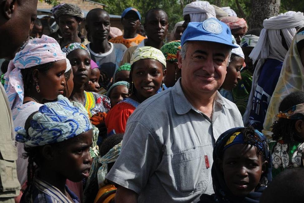 SRSG wearing a UN blue baseball cap in a crowd of people.