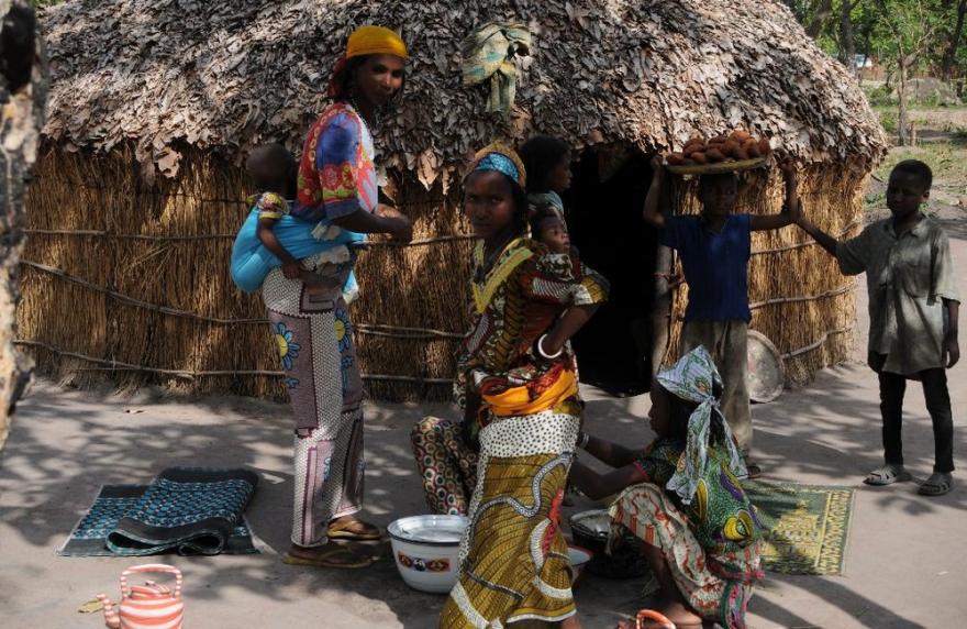 A UN truck is stationed on a dirt road with trees and a small structure nearby