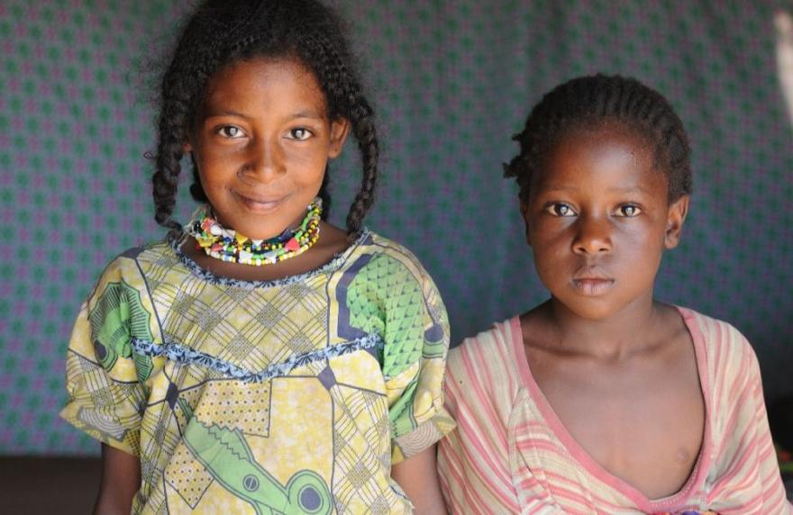 UN personnel stand beside a vehicle near a compound with metal fencing