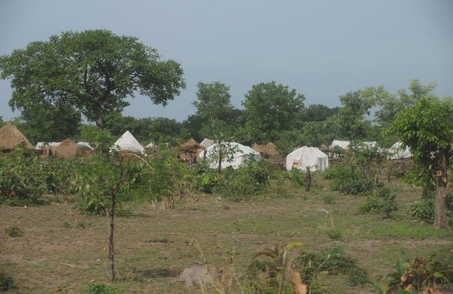 A UN vehicle is parked beside a small building with a tin roof and trees around.