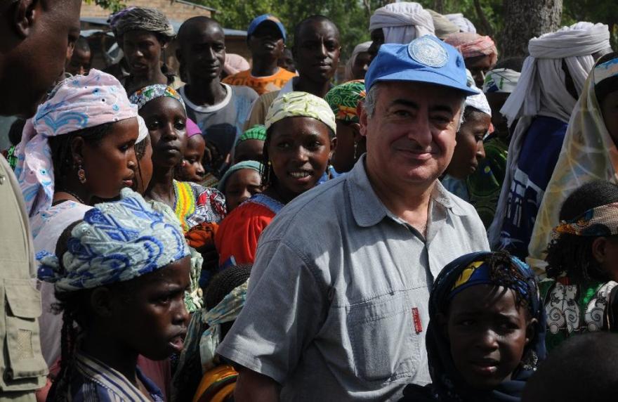 SRSG wearing a UN blue baseball cap in a crowd of people.